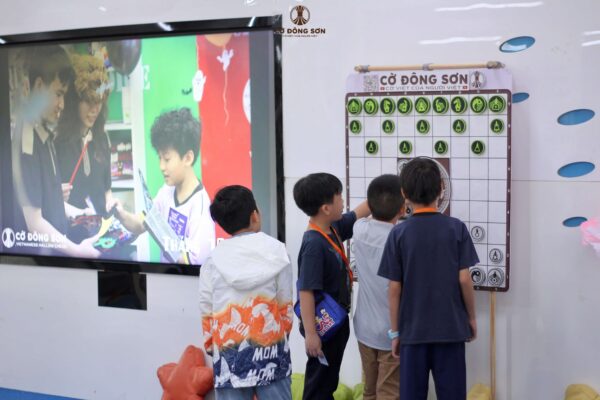 Các kỳ thủ nhí đang tìm hiểu luật chơi Cờ Đông Sơn qua bàn cờ lớn treo tường tại Thư viện KHTH TP.HCM.