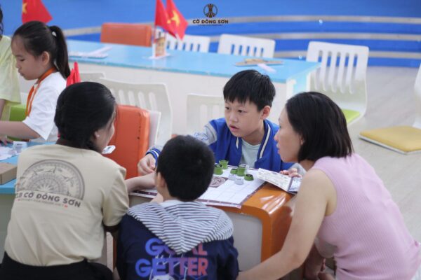 Phụ huynh và nhân viên hỗ trợ đang cùng bé trai thảo luận về chiến thuật chơi cC Đông Sơn.