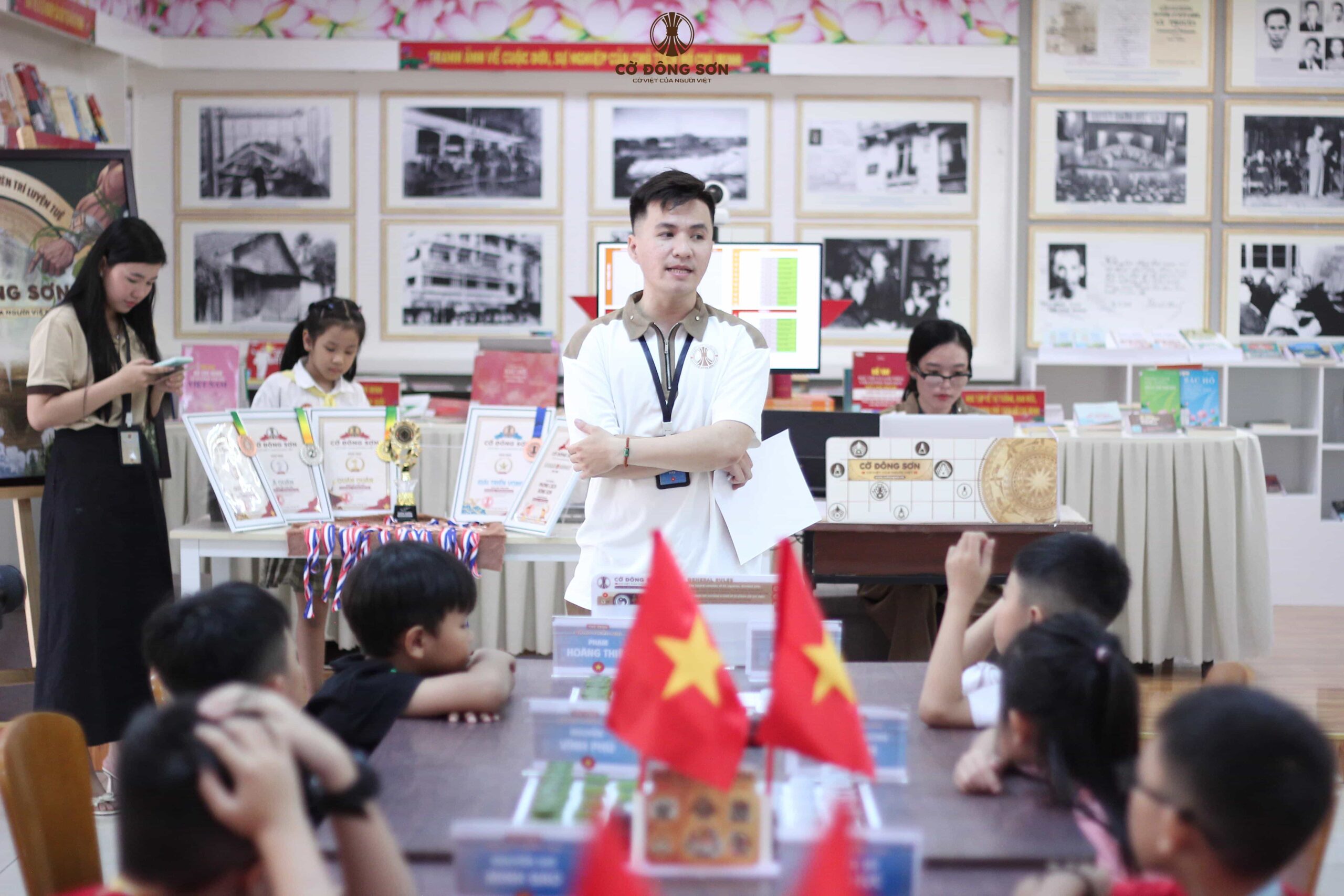 Đại diện Ban tổ chức đứng trước khu vực trưng bày cúp và huy chương, dặn dò các kỳ thủ nhí trước khi bắt đầu Giải đấu Cờ Đông Sơn lần 2.