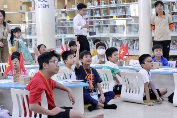 Các bạn nhỏ chăm chú theo dõi và hào hứng giơ tay phát biểu trong buổi sinh hoạt Cờ Đông Sơn tại không gian Thư viện Khoa học Tổng hợp TP.HCM.