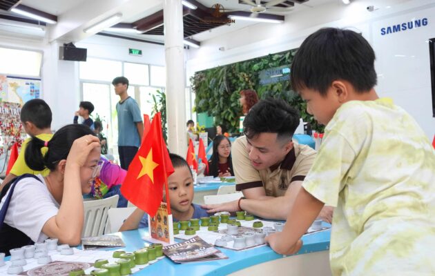 Đại diện dự án nhiệt tình hướng dẫn các kỳ thủ nhí dưới sự quan sát và nụ cười rạng rỡ của phụ huynh trong buổi sinh hoạt Cờ Đông Sơn.