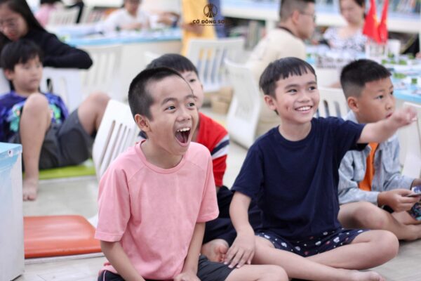 Biểu cảm phấn khích và nụ cười rạng rỡ của các kỳ thủ nhí khi khám phá cách tính điểm thi đấu tại buổi sinh hoạt Cờ Đông Sơn, sẵn sàng cho Cúp Hùng Vương 2026.