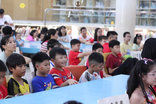 Hình ảnh các kỳ thủ nhí cùng phụ huynh chăm chú theo dõi và cười tươi rạng rỡ dưới hàng ghế khán giả tại Giải đấu Cờ Đông Sơn lần 2.