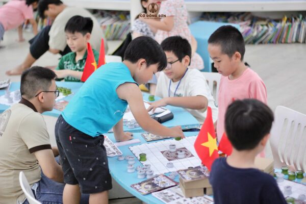 Kỳ thủ nhí tập trung cao độ, đứng hẳn dậy để quan sát và áp dụng cách tính điểm thi đấu trong buổi sinh hoạt Cờ Đông Sơn nhằm chuẩn bị cho Cúp Hùng Vương 2026.