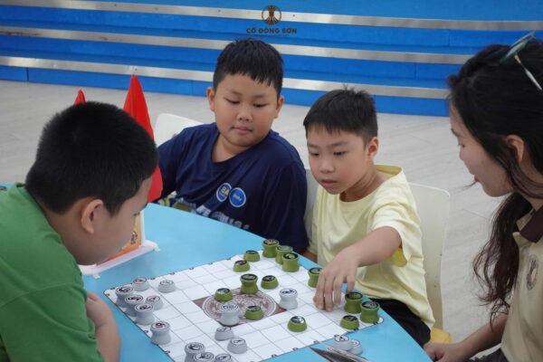 Kỳ thủ nhí tự tin đi nước cờ quyết định dưới sự quan sát của đồng đội và ban tổ chức trong buổi sinh hoạt Cờ Đông Sơn.