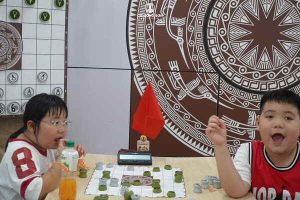 Khoảnh khắc hài hước với biểu cảm ngạc nhiên của bé trai và vẻ bình thản của bé gái trong một ván Cờ Đông Sơn tại CLB Lam Sơn.