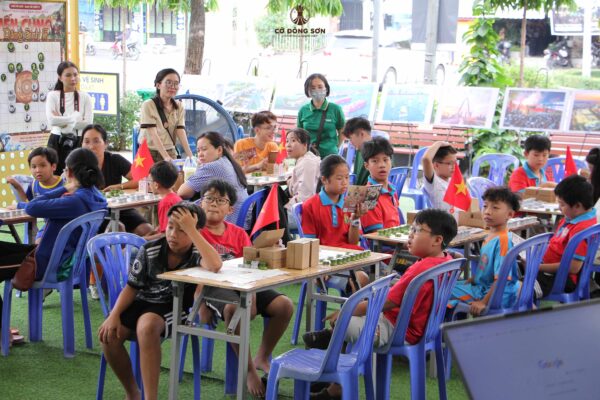 Đông đảo các bạn nhỏ và phụ huynh đang chăm chú lắng nghe hướng dẫn và trực tiếp trải nghiệm board game Cờ Đông Sơn tại Đường sách TP. Thủ Đức.