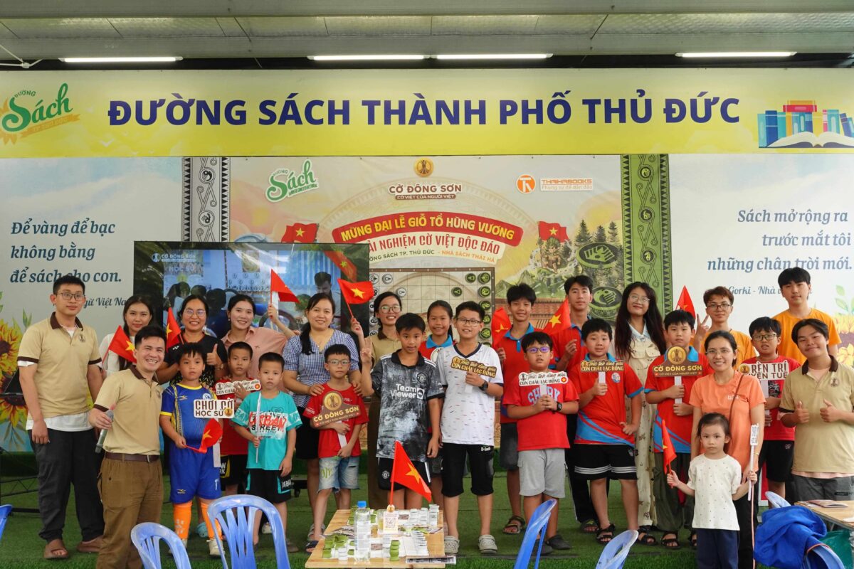 Bức ảnh tập thể ban tổ chức, phụ huynh và các em nhỏ mỉm cười rạng rỡ tham gia sự kiện trải nghiệm board game Cờ Đông Sơn tại Đường sách TP. Thủ Đức.