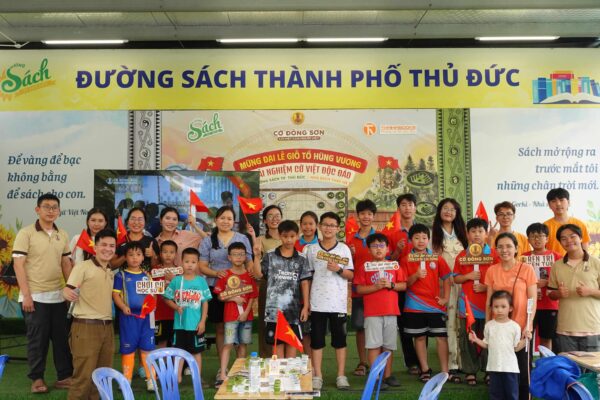 Bức ảnh tập thể ban tổ chức, phụ huynh và các em nhỏ mỉm cười rạng rỡ tham gia sự kiện trải nghiệm board game Cờ Đông Sơn tại Đường sách TP. Thủ Đức.