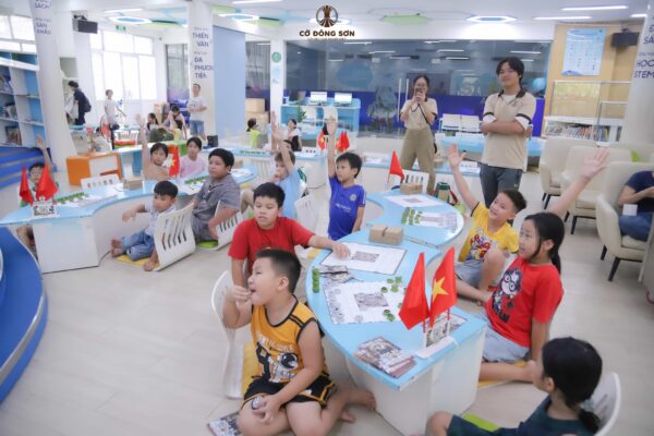 toàn cảnh các bạn nhỏ hào hứng giơ cao tay phát biểu ý kiến trong giờ học tương tác sinh động của Khóa hè Cờ Đông Sơn tại Thư viện.