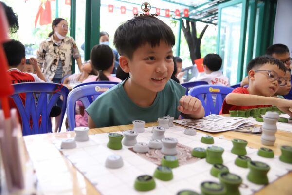 Cận cảnh nụ cười rạng rỡ đầy phấn khích của một cậu bé khi tìm ra nước cờ thông minh trong buổi giao lưu tại Khóa hè Cờ Đông Sơn.