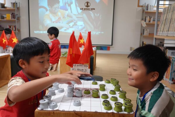 Hai kỳ thủ nhí mỉm cười vui vẻ khi đang thi đấu thực chiến tại không gian