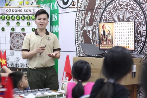 Huấn luyện viên hướng dẫn các kỳ thủ nhí tham gia minigame đoán chữ lịch sử trong buổi học Cờ Đông Sơn Khóa 1 Hè 2026 tại CLB Lam Sơn.