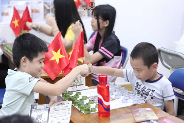 Hai kỳ thủ nhí đập tay thể hiện tinh thần fair-play khi thi đấu Cờ Đông Sơn tại CLB Lam Sơn trong Khóa 1 Hè 2026.